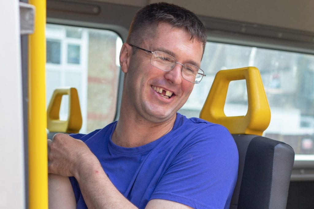 A service user sitting in the mini bus and smiling