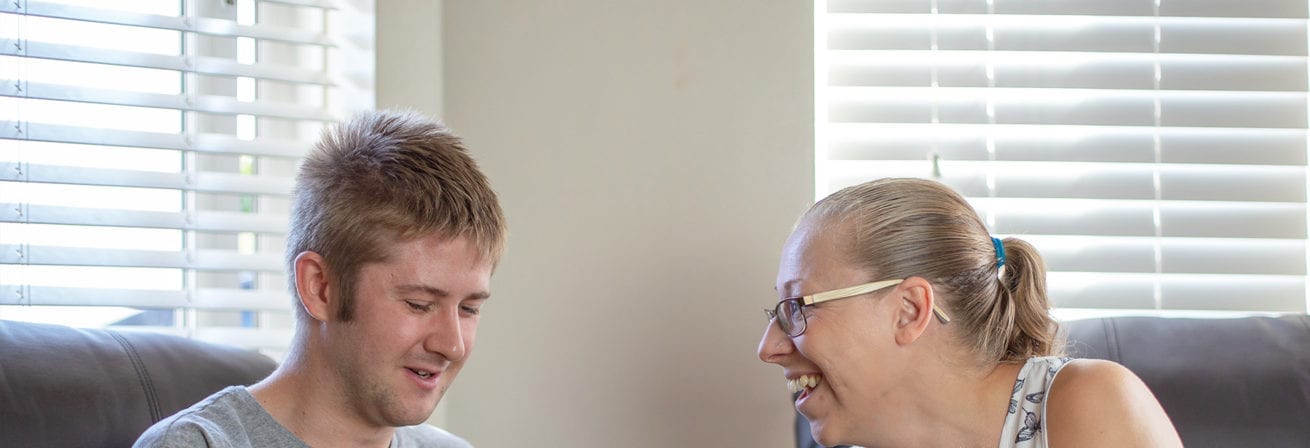 A service user and carer smile at a phone screen together