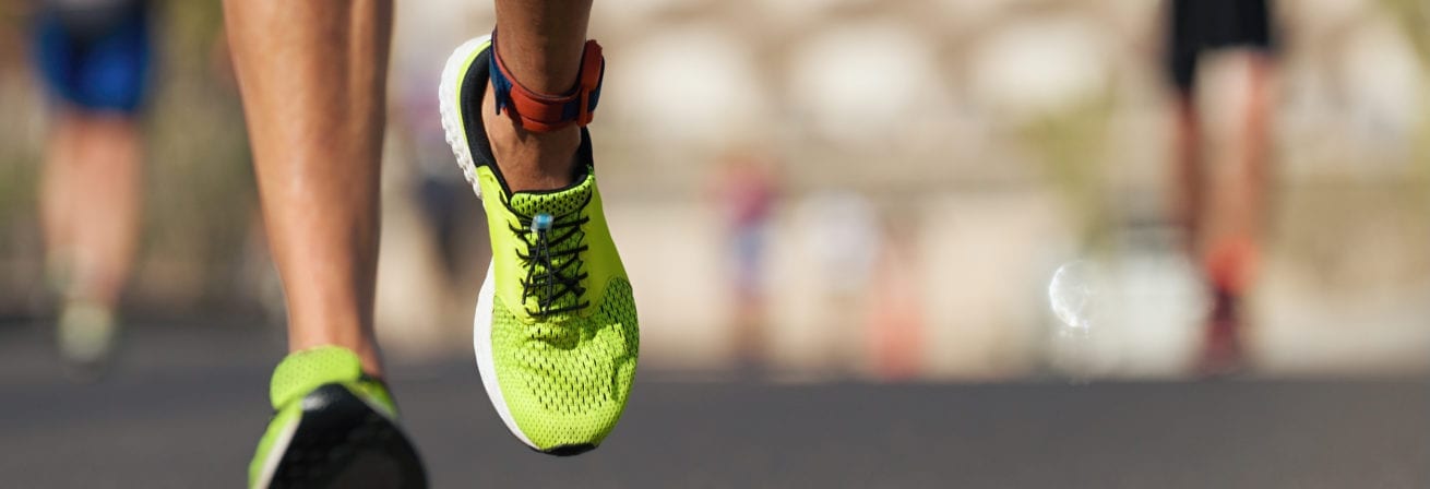 Runners feet running on road close up on shoe, male triathlete runner.