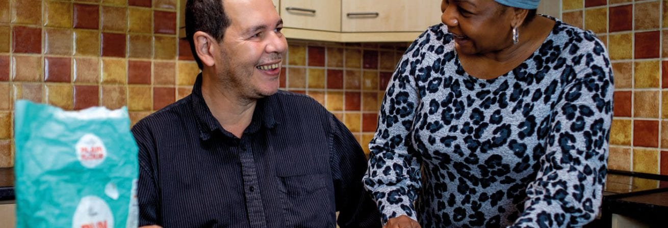 A man from our mental health service is being supported by a staff member to cook dinner.