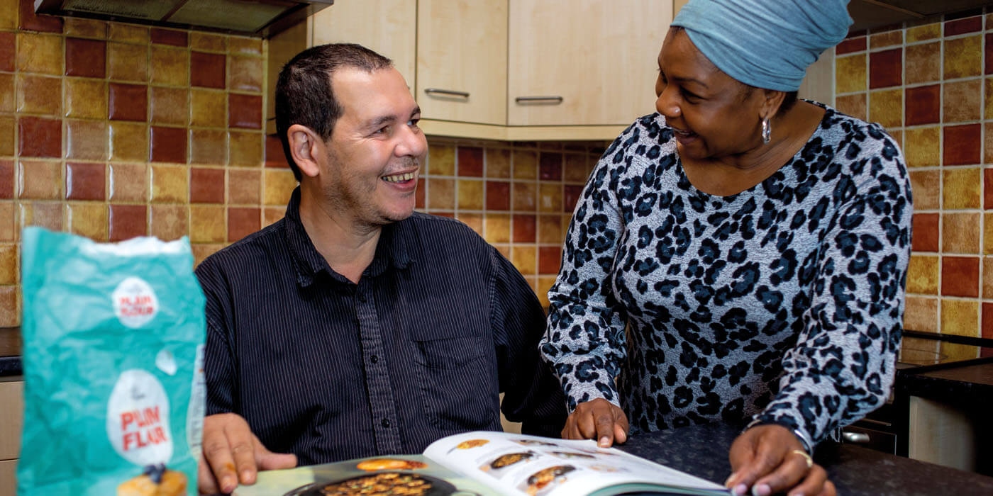 A man from our mental health service is being supported by a staff member to cook dinner.